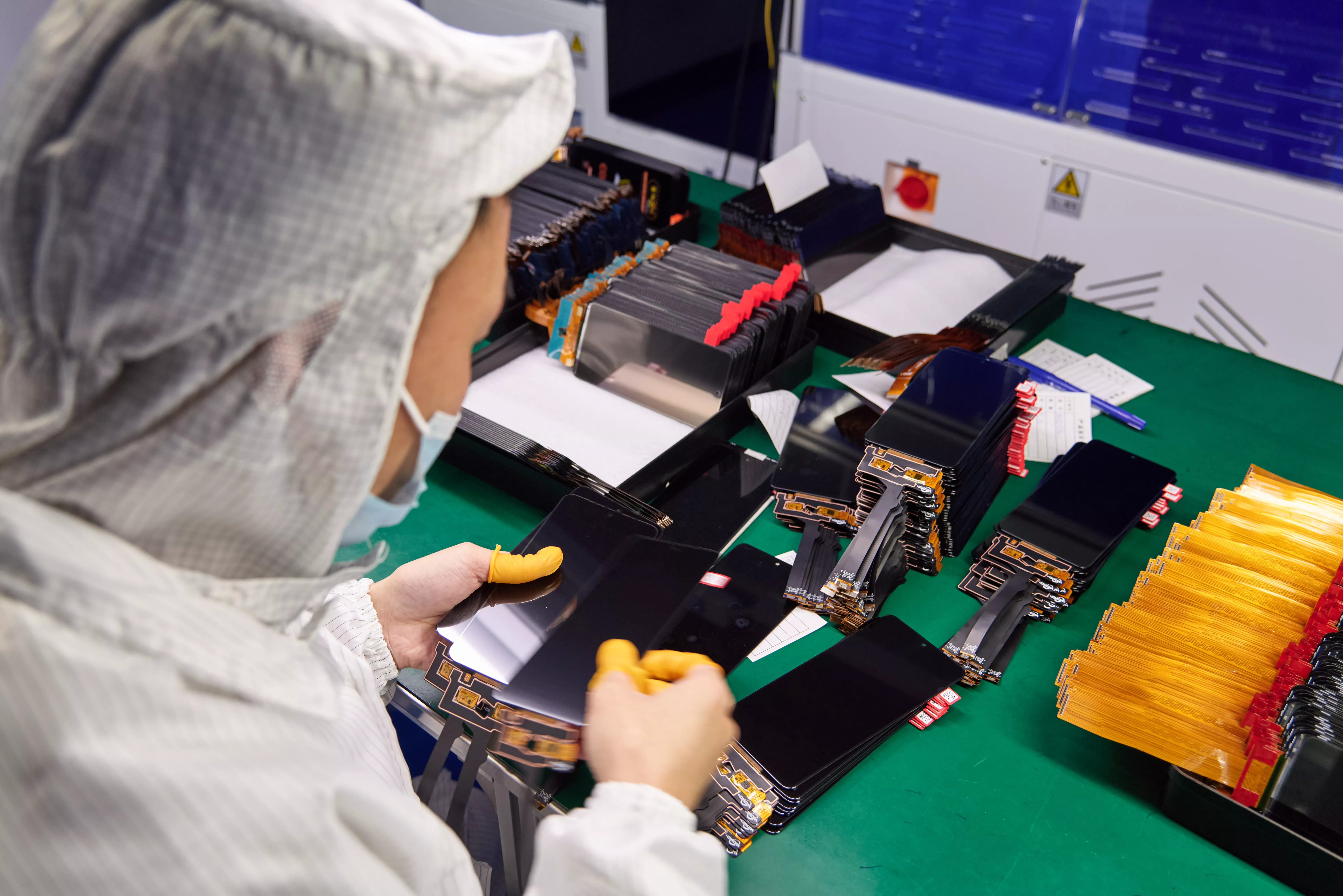Workers inspecting mobile phone replacement screens at YEZONE factory